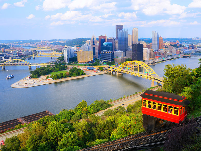 A trolley goes down the Duquesne Incline. In the distance is Pittsburgh's Golden Triangle.