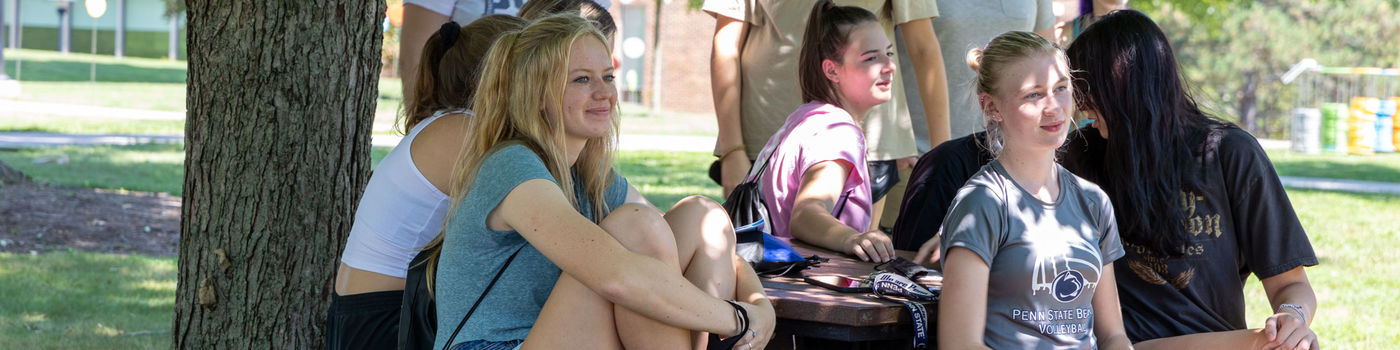 Students sit outside at a picnic table